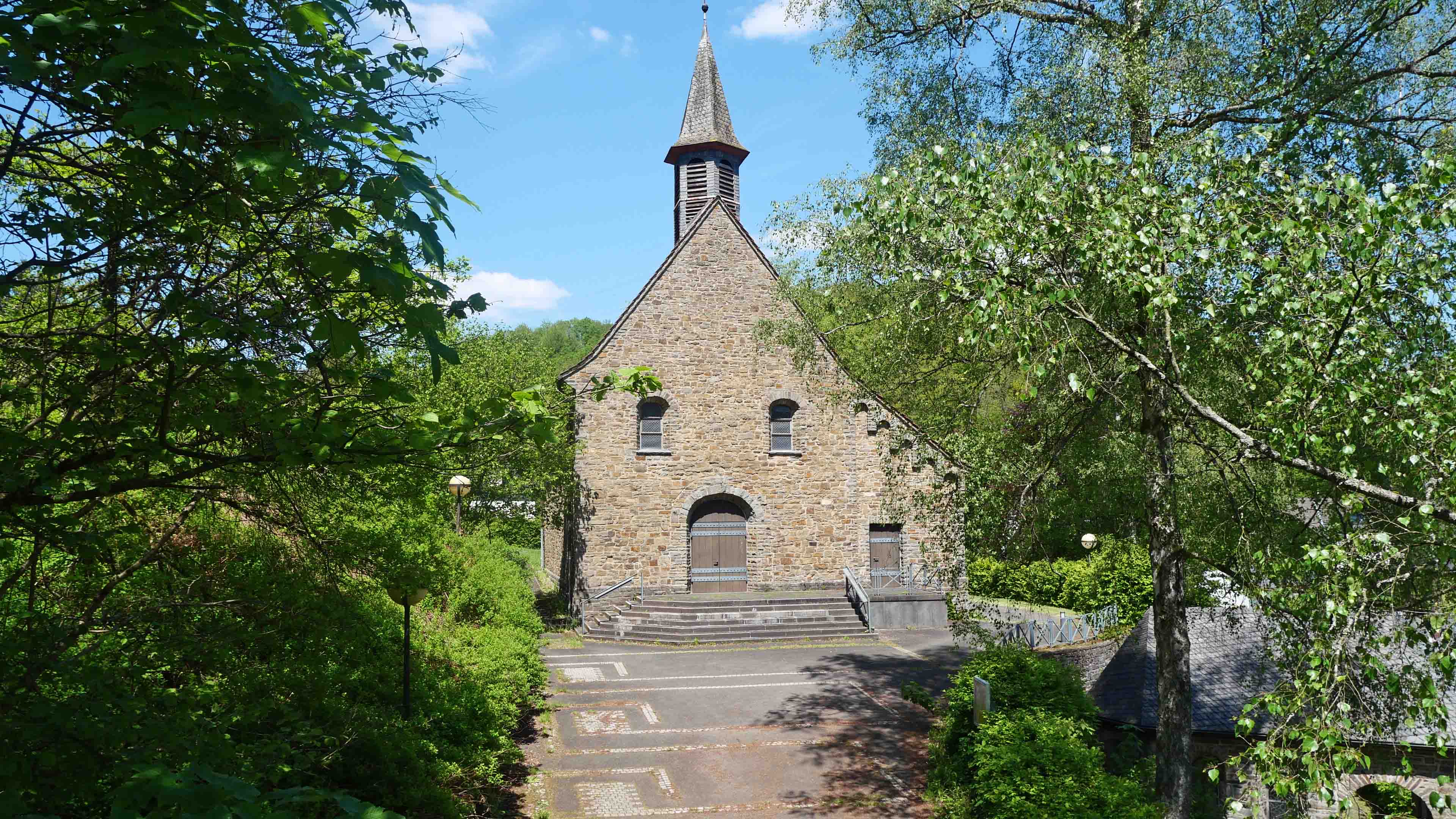 Morsbach-Ellingen: Stilvolle, kleine Bruchsteinkirche, Kirchenvorplatz/lange gepflasterte Auffahrt 
