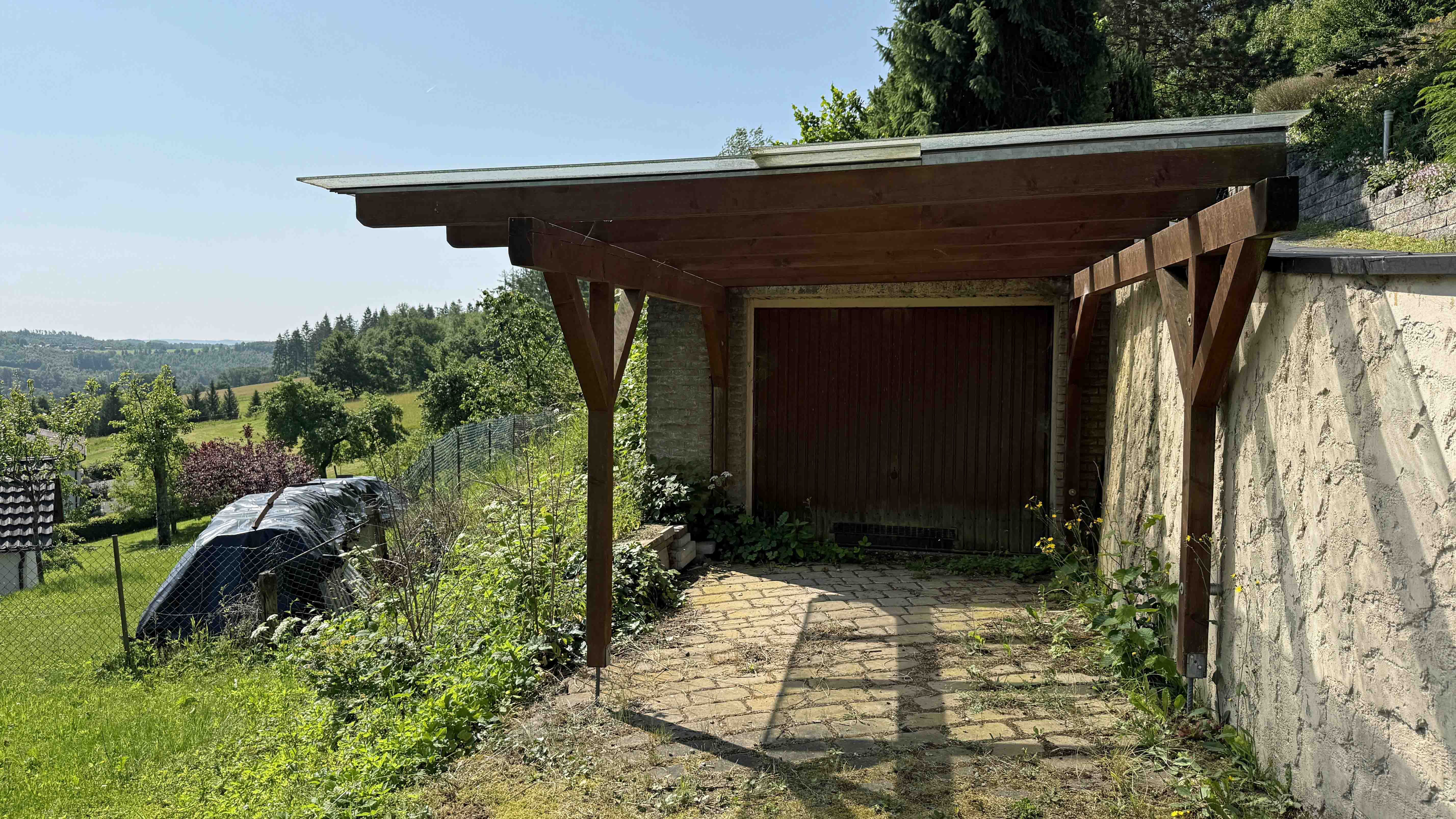 Morsbach-Herbertshagen: besondere Lage - besonderes Haus, Grundstückseinzäunung. Garage mit Carport davor.